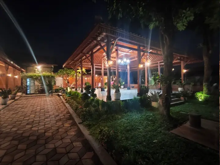 Pendopo utama dengan tiang kayu dan pencahayaan malam.