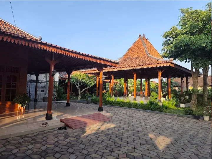 Area halaman yang lapang dengan arsitektur Joglo dan taman hijau.